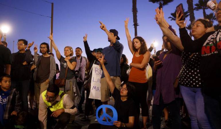 Protestantes alzan sus manos con el símbolo de la paz en California.