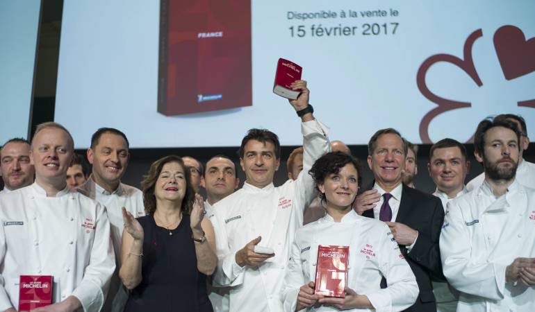 El chef francés Yannick Alleno (c) muestra la edición francesa de la Guía Michelín 2017.