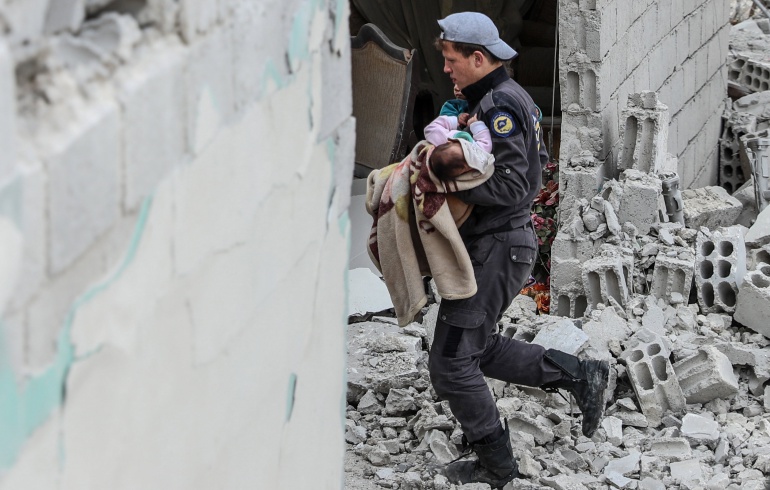 Un voluntario de los Cascos Blancos rescata a un bebé tras un ataque aéreo en Douma, Siria.