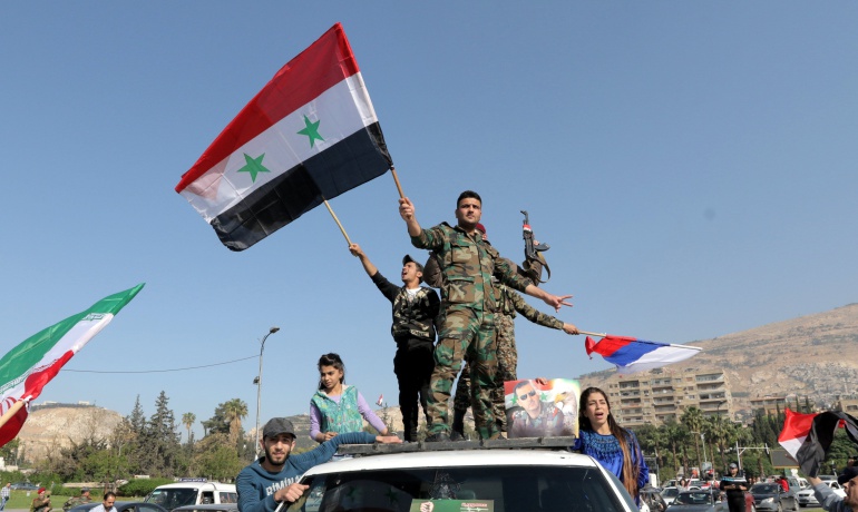 Soldados sirios ondean su bandera nacional junto con las de Irán y Rusia durante una concentración en apoyo al Gobierno sirio celebrada en la plaza de Umayyad en Damasco.