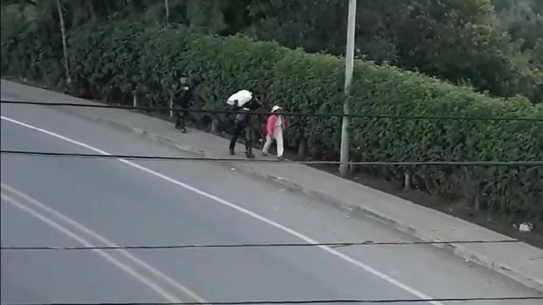 Policías ayudan a campesina a transportar su carga en medio de las trochas