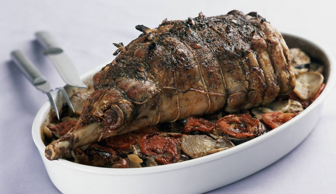 Pierna de cordero asado sobre papas, berenjenas y tomates