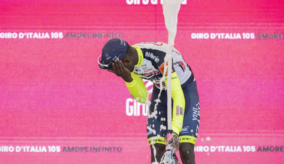 Biniam Girmay en el momento que fue impactado por el corcho de la botella de vino al celebrar el triunfo en la décima etapa del Giro. Biniam Girmay en el momento que fue impactado por el corcho de la botella de vino al celebrar el triunfo en la décima etapa del Giro.