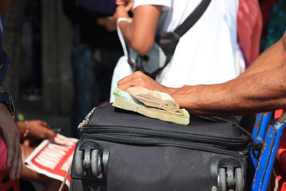 Un venezolano cuida sus fajos de bolívares: a pesar de la devaluación, son su único pasaporte para empezar una vida en Colombia. Un venezolano cuida sus fajos de bolívares: a pesar de la devaluación, son su único pasaporte para empezar una vida en Colombia.