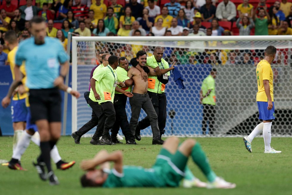 Un fan es detenido por los miembros de seguridad del Estadio Nacional de Brasilia durante el partido Brasil vs Iraq que terminó empatado 0-0. Un fan es detenido por los miembros de seguridad del Estadio Nacional de Brasilia durante el partido Brasil vs Iraq que terminó empatado 0-0.