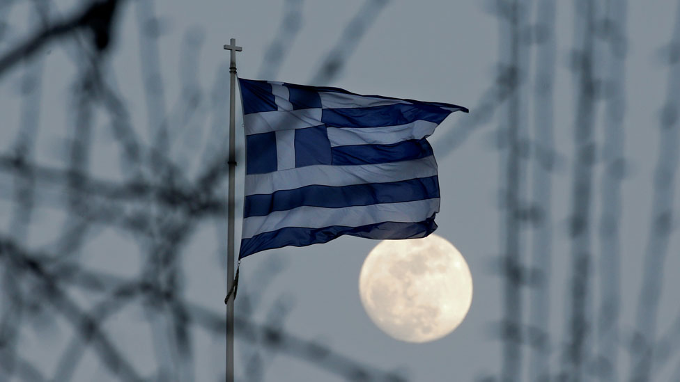 Una bandera de Grecia ondea frente a la Luna vista sobre Atenas. Una bandera de Grecia ondea frente a la Luna vista sobre Atenas.